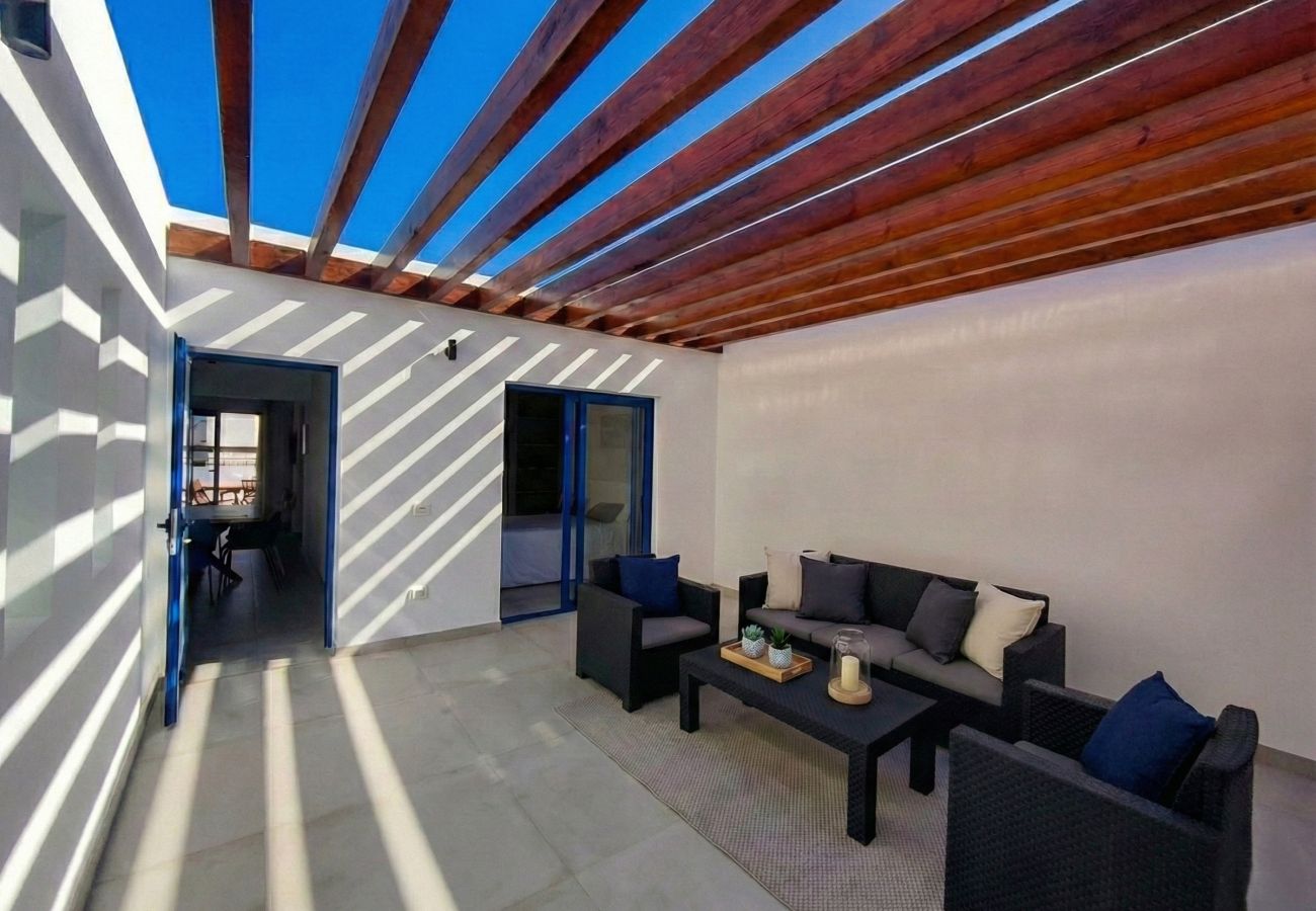 Sofás oscuros en patio con sombras geométricas