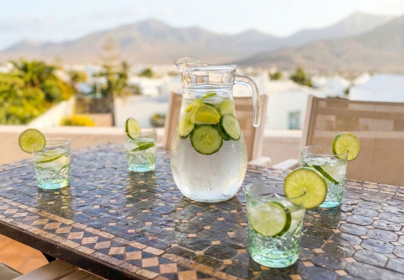 Bebidas refrescantes en mesa de terraza con piscina al fondo