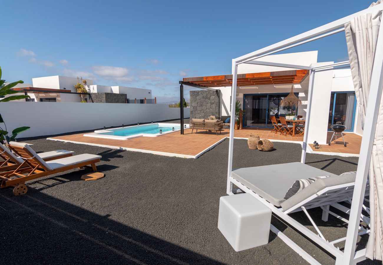 Terraza villa vacacional con piscina, cama balinesa y mobiliario exterior