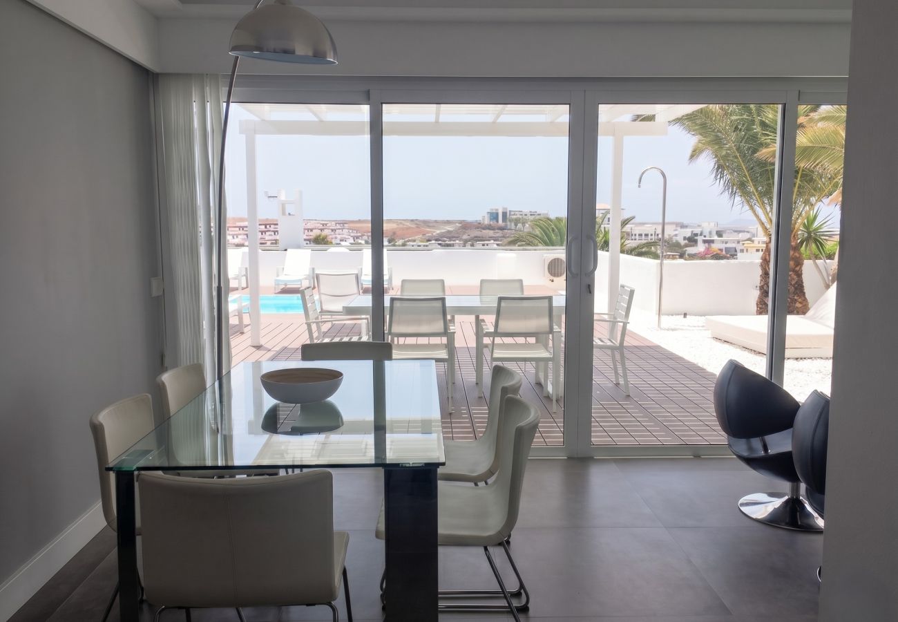 Mesa de comedor de cristal con sillas modernas mirando hacia la terraza exterior