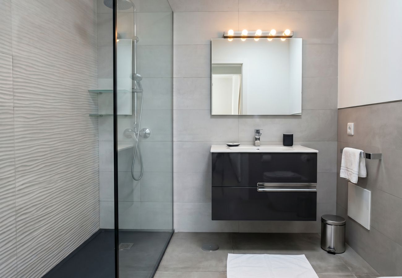 Cuarto de baño moderno con ducha de cristal, azulejos grises y mueble negro