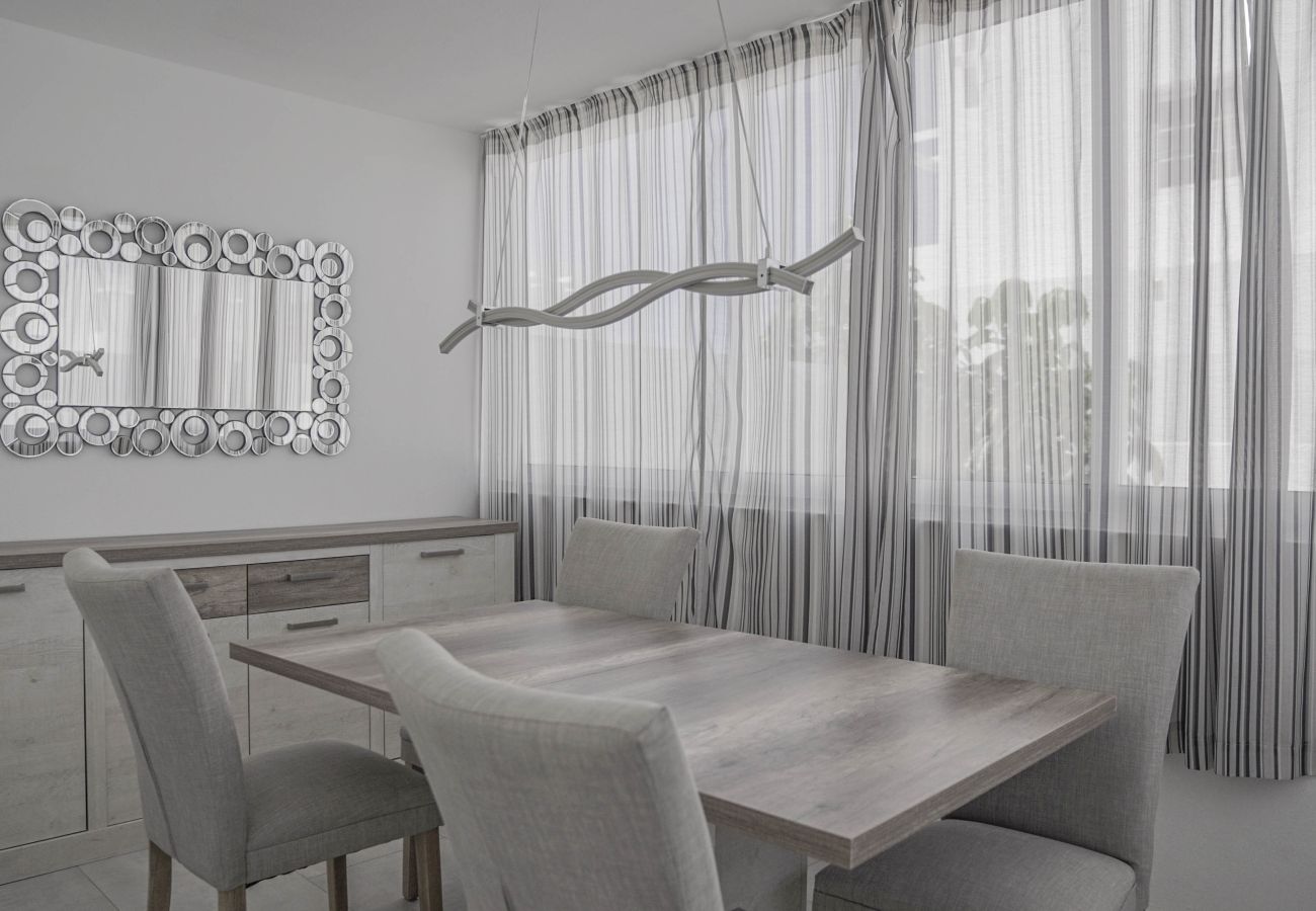 Mesa de comedor interior con sillas grises y espejo en Villa Marina