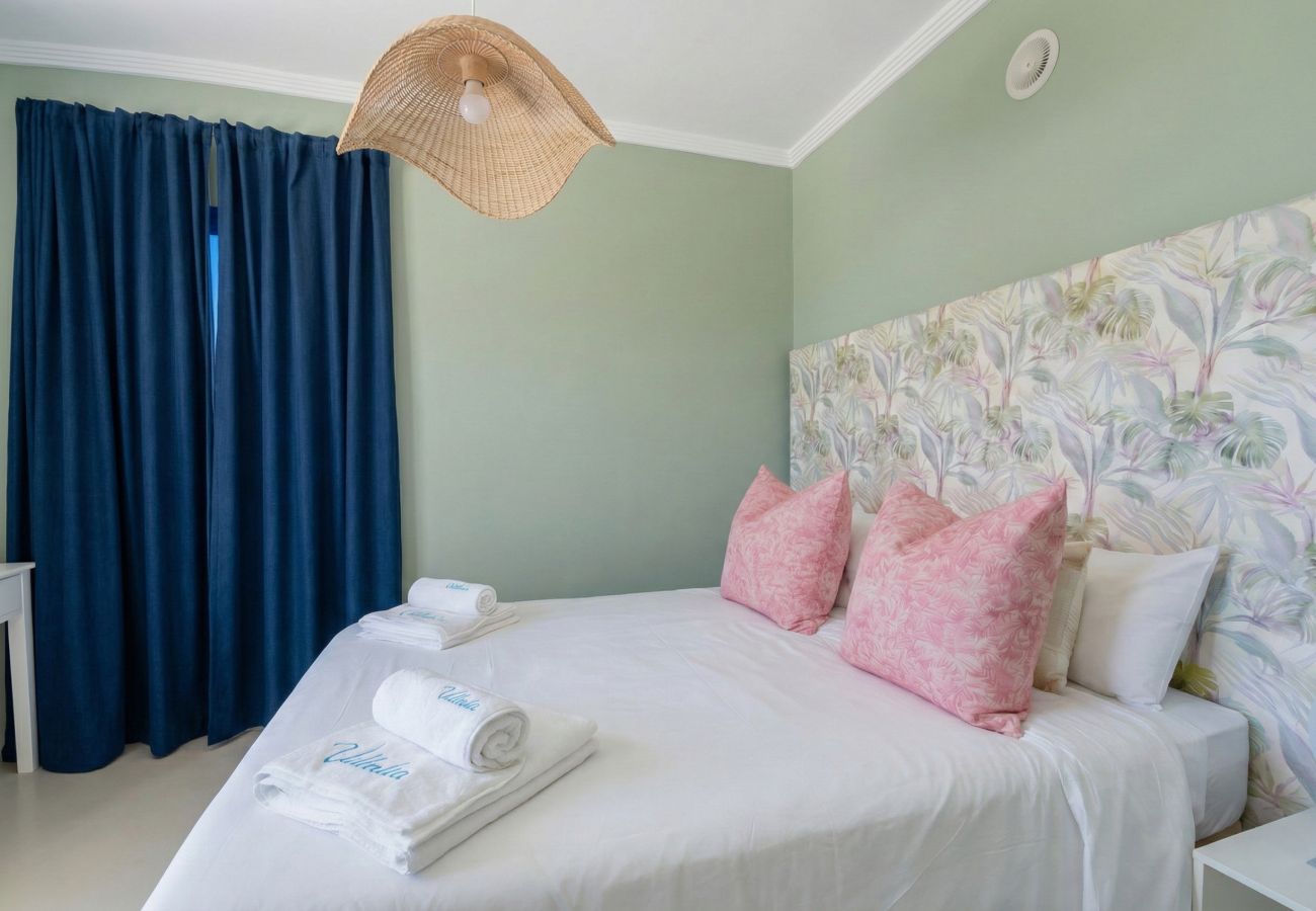 Double bed with pink cushions and green wall