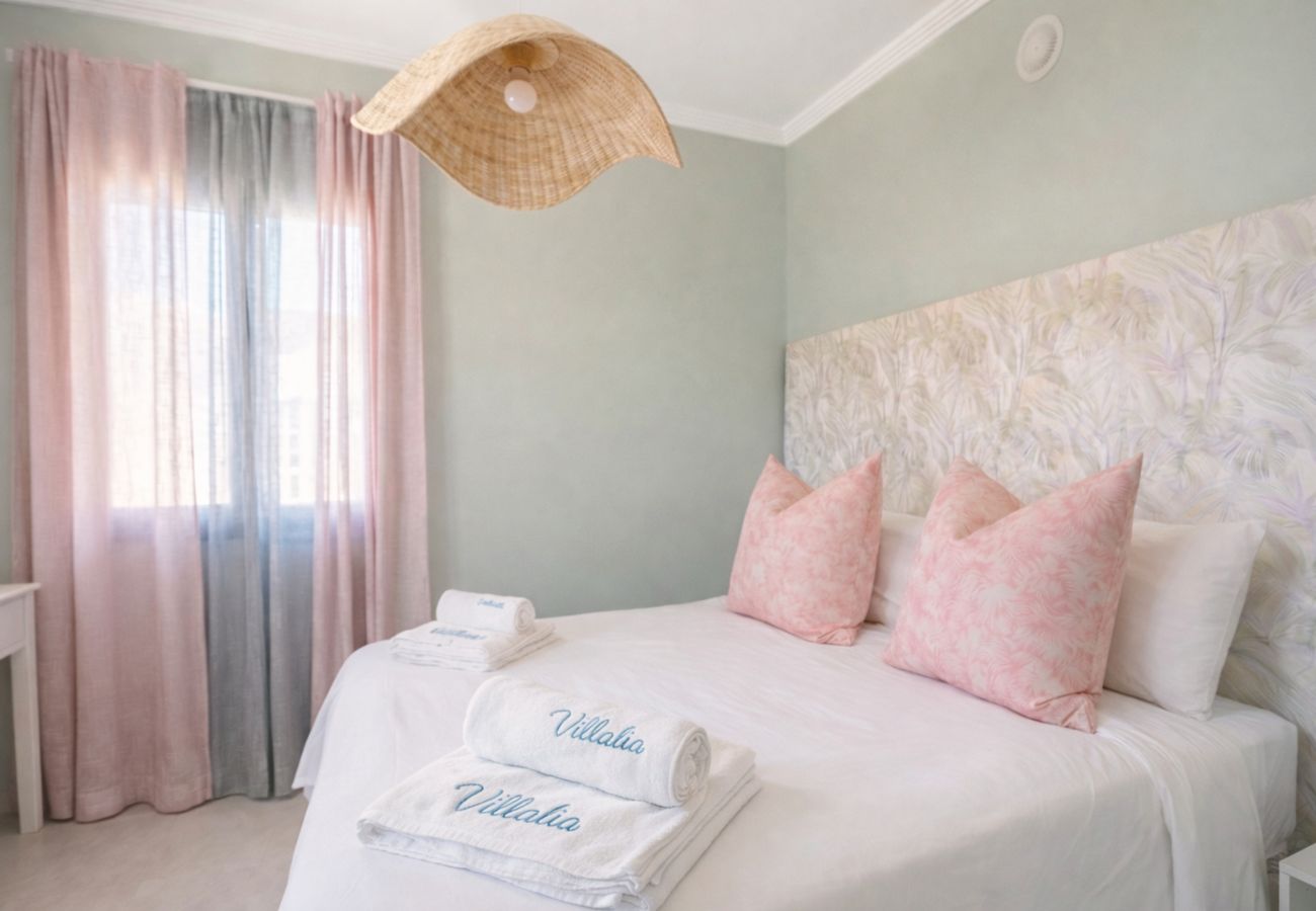 Double bed with pink cushions and green wall