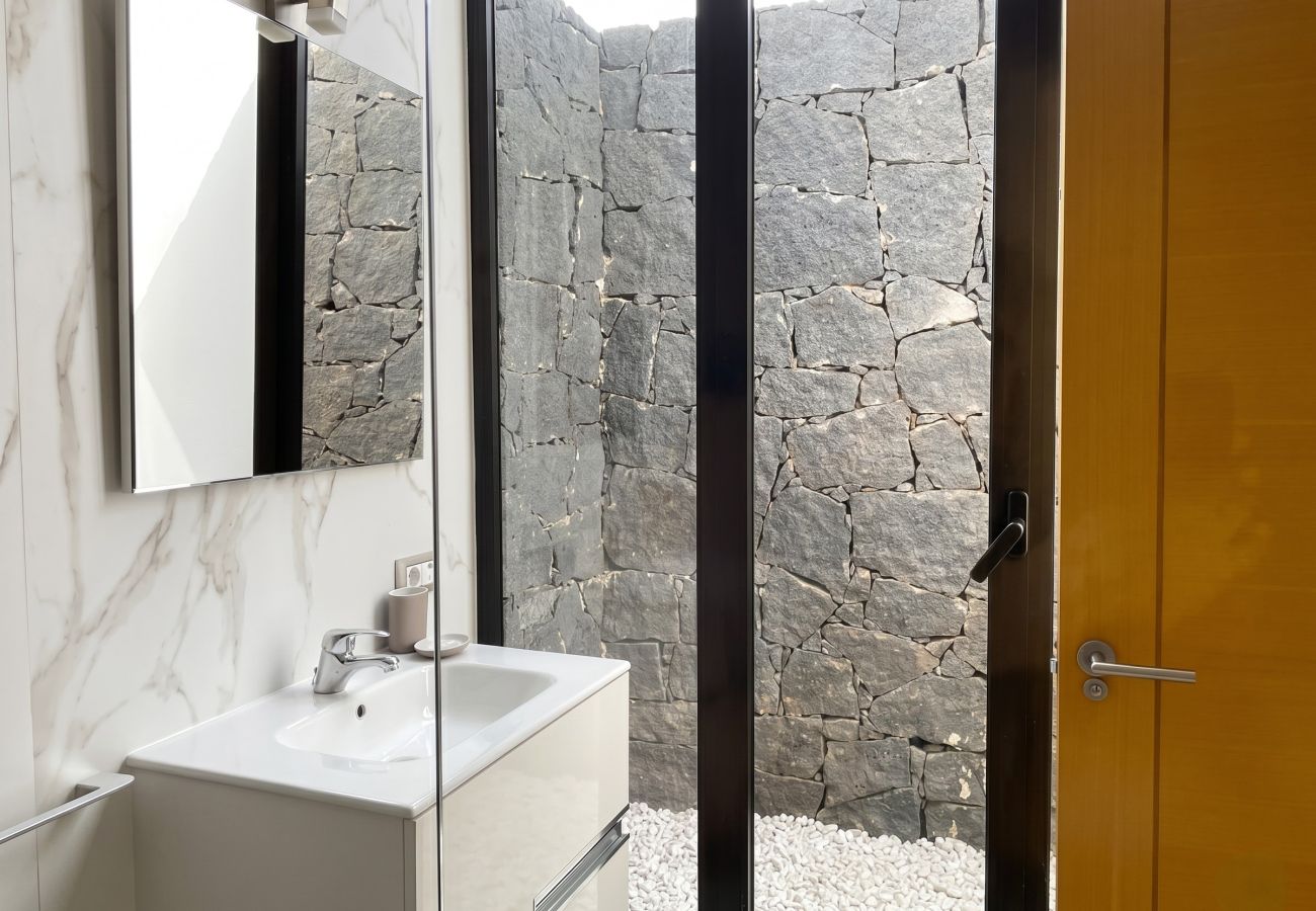 Modern sink with a large window facing a volcanic stone wall.