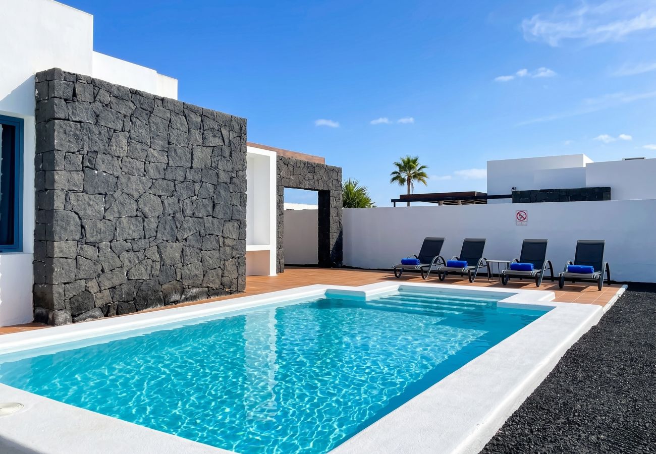 Private pool with sun loungers in a Lanzarote villa.
